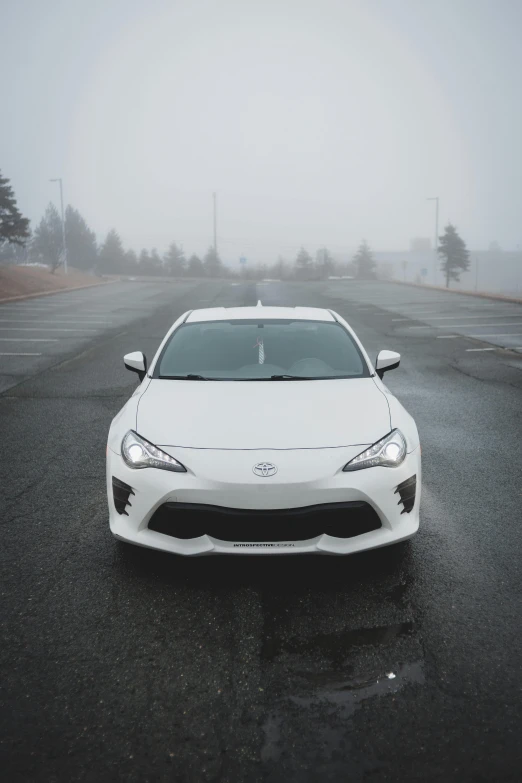 a white sports car sits parked on a foggy road