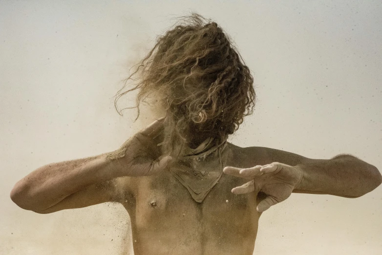 a man holds his arm back while standing on a beach