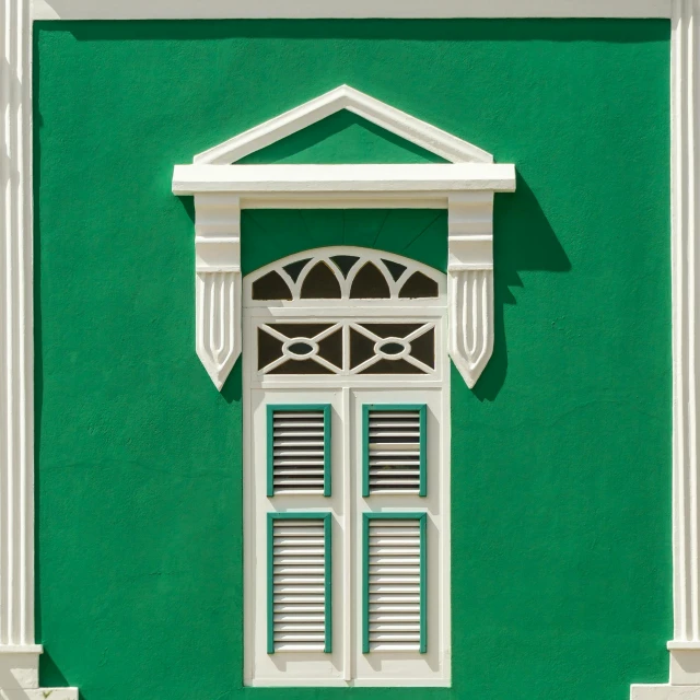 a green wall with a white window with arched doors