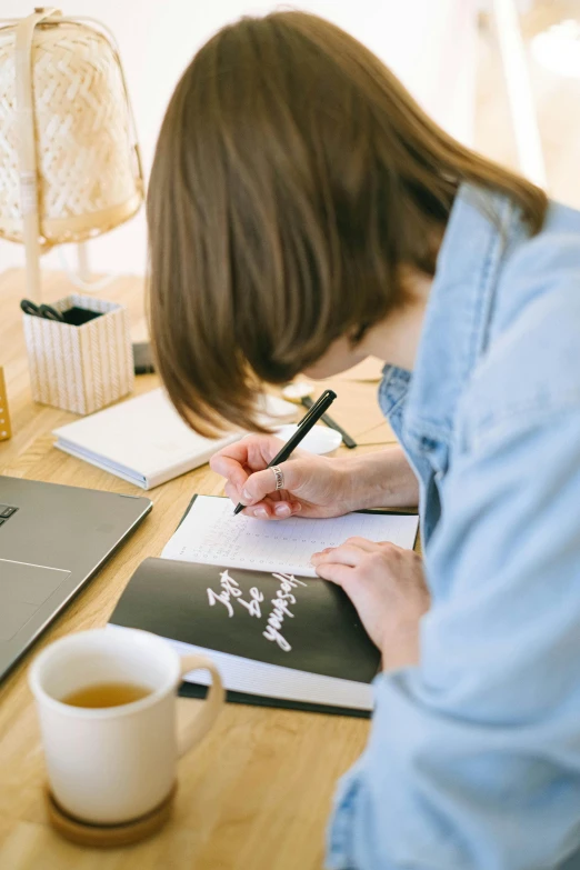 a woman writing on paper on top of a table