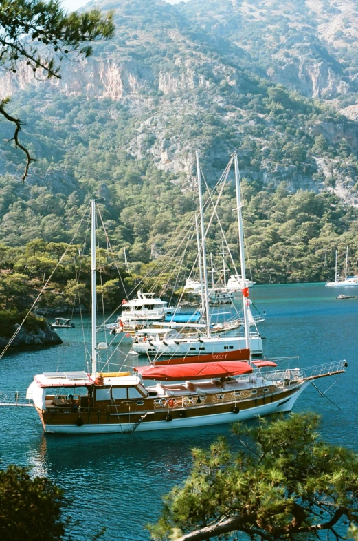 a row of sailboats sitting on top of a lake next to tall mountains