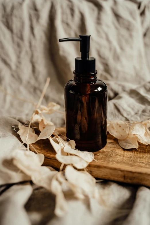 a soap dispenser on a table with dried flowers