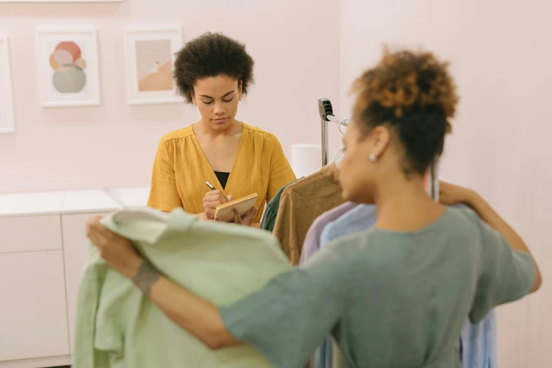 a woman is drying clothes and another stands behind her