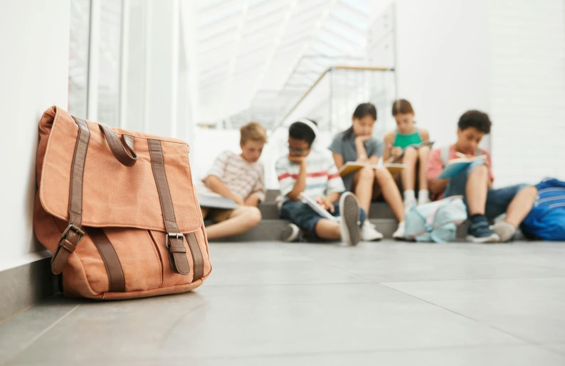 three s and one older boy sit on the floor in front of a backpack