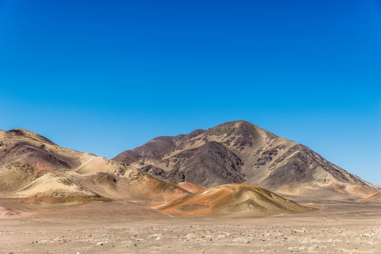 some mountains with brown dirt and blue skies