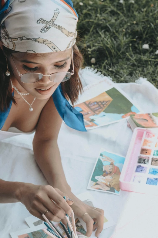 a woman sitting on a blanket painting pictures on the ground