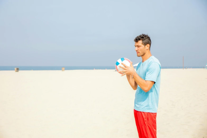 a man holds a beach ball on the sand