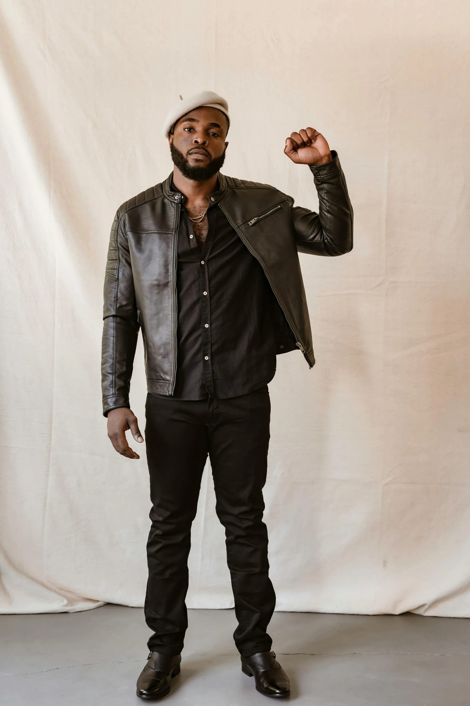 a black man in a black jacket standing in front of a white backdrop