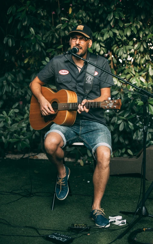 a man playing an acoustic guitar while standing near a microphone