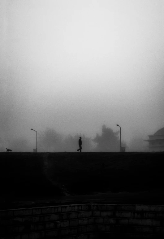 a person walking along a foggy street with a person walking on the sidewalk