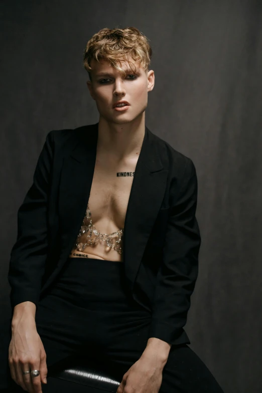 a young woman posing in a black suit and chain