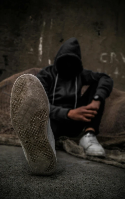 a man sitting in the street with his foot on his knees