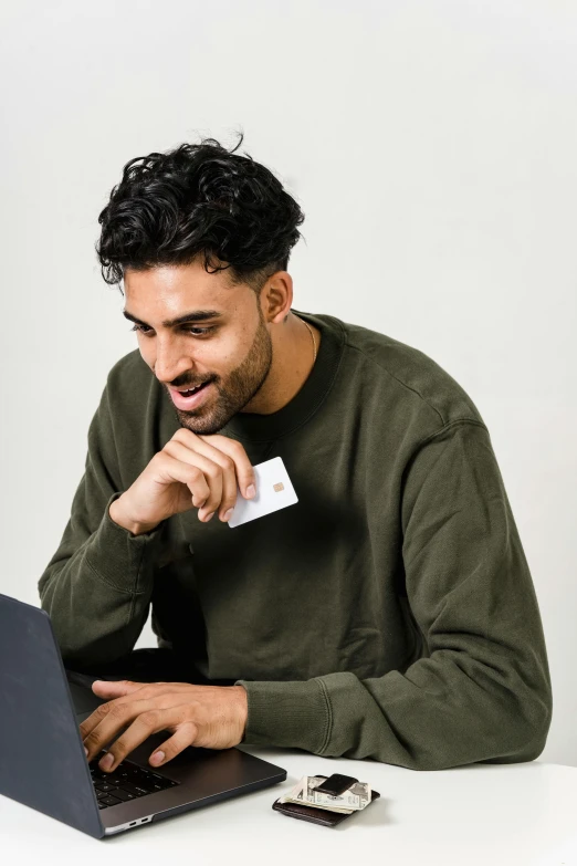 the young man is enjoying his laptop with a credit card