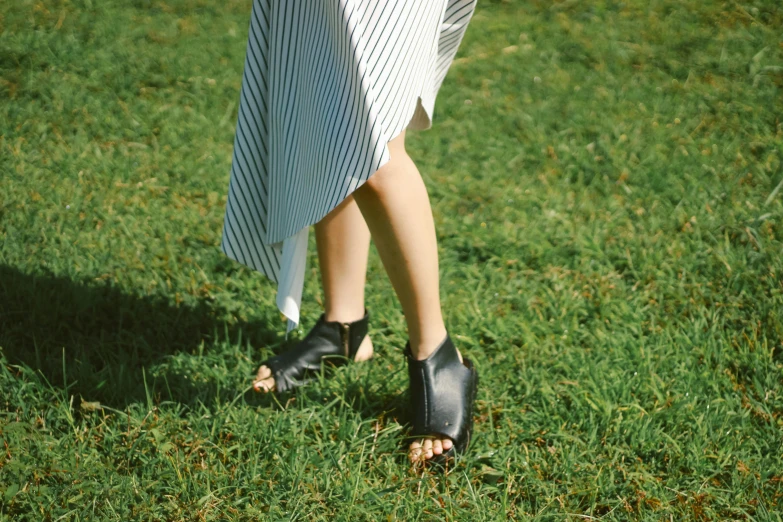 a woman in slippers and heels walking across a field