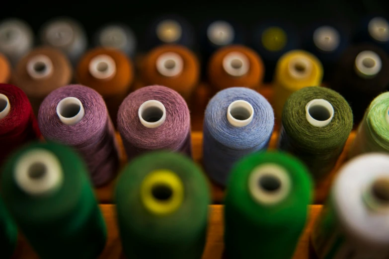 there are many colors of sewing threads sitting in a bin