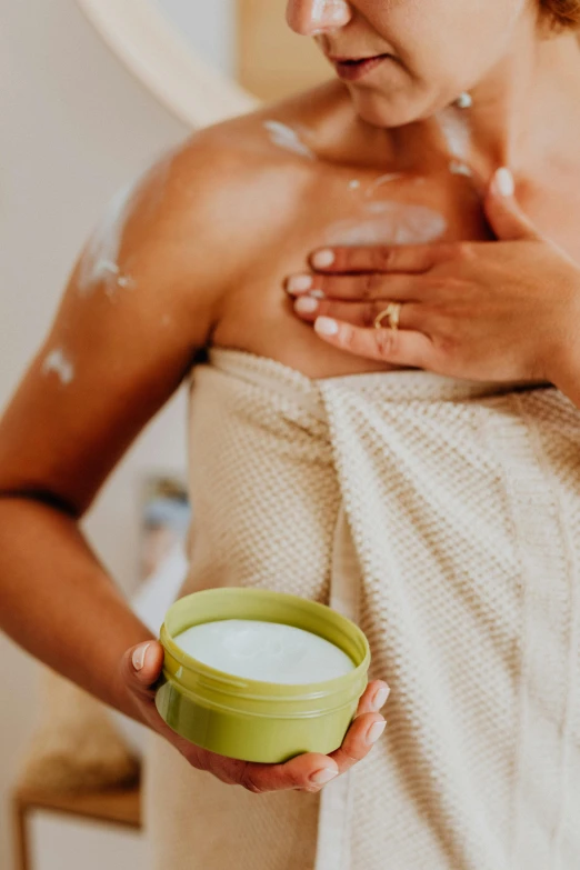 woman wearing a towel holding a cup of soap