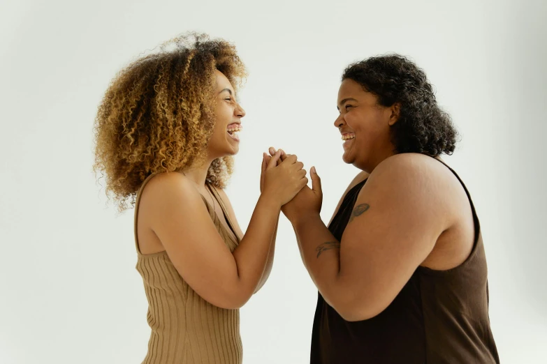 two women are standing with their hands together