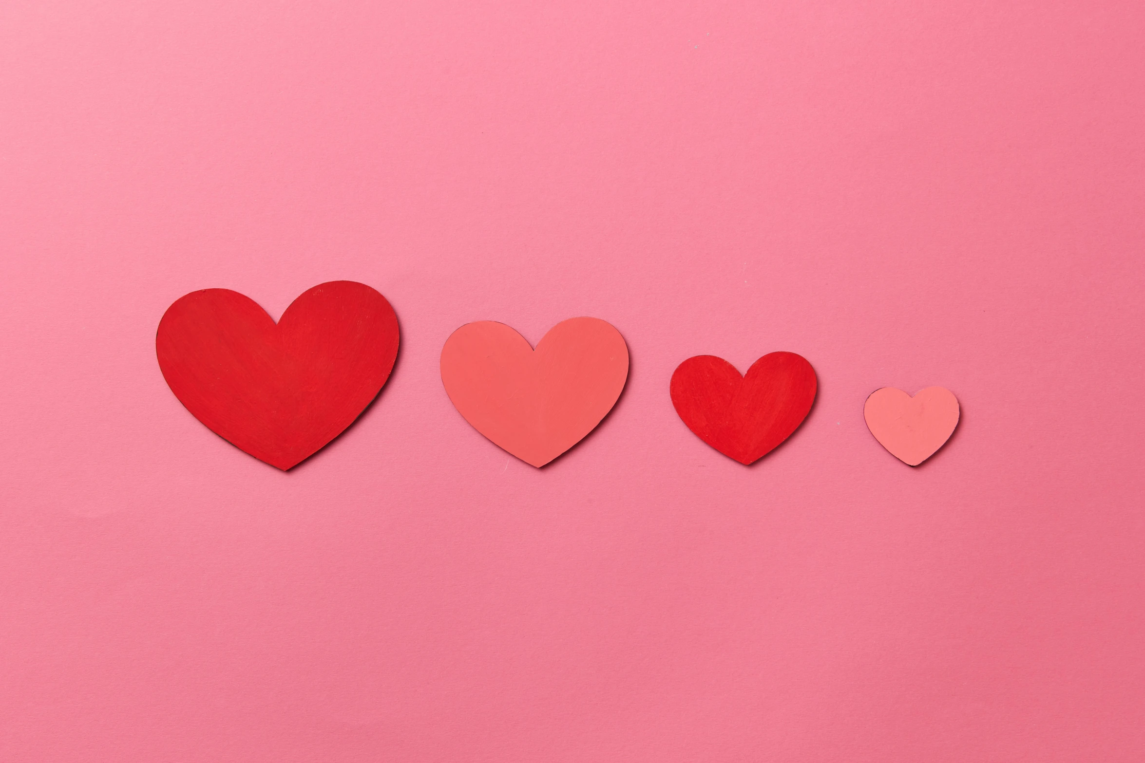 red hearts and other cutouts on a pink background