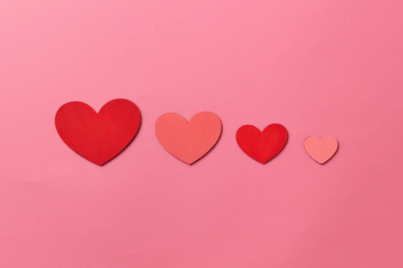 red hearts and other cutouts on a pink background