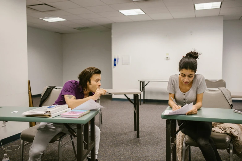 two women are sitting at their desks while writing