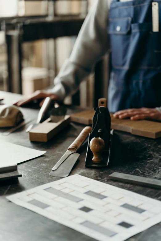 a person holding scissors near a table filled with various woodwork and various materials