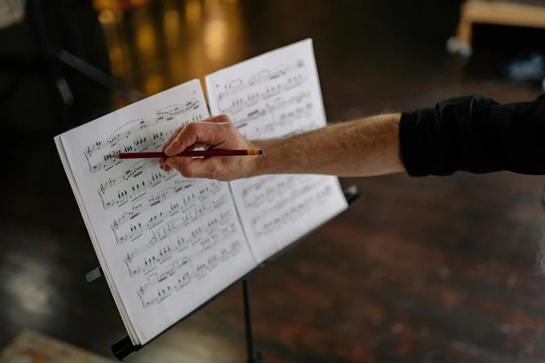 a person holding a piece of music paper next to some writing