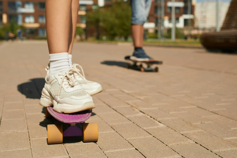 a person in tennis shoes standing on a skate board