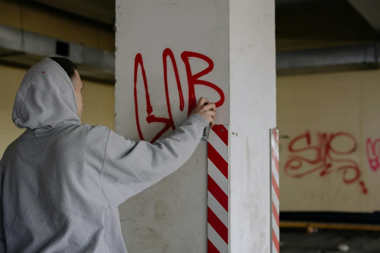 a man with a grey jacket is writing on a red and white pole
