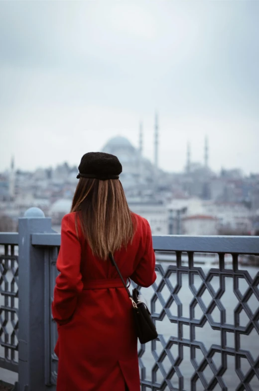 woman wearing a red coat looking out over the city