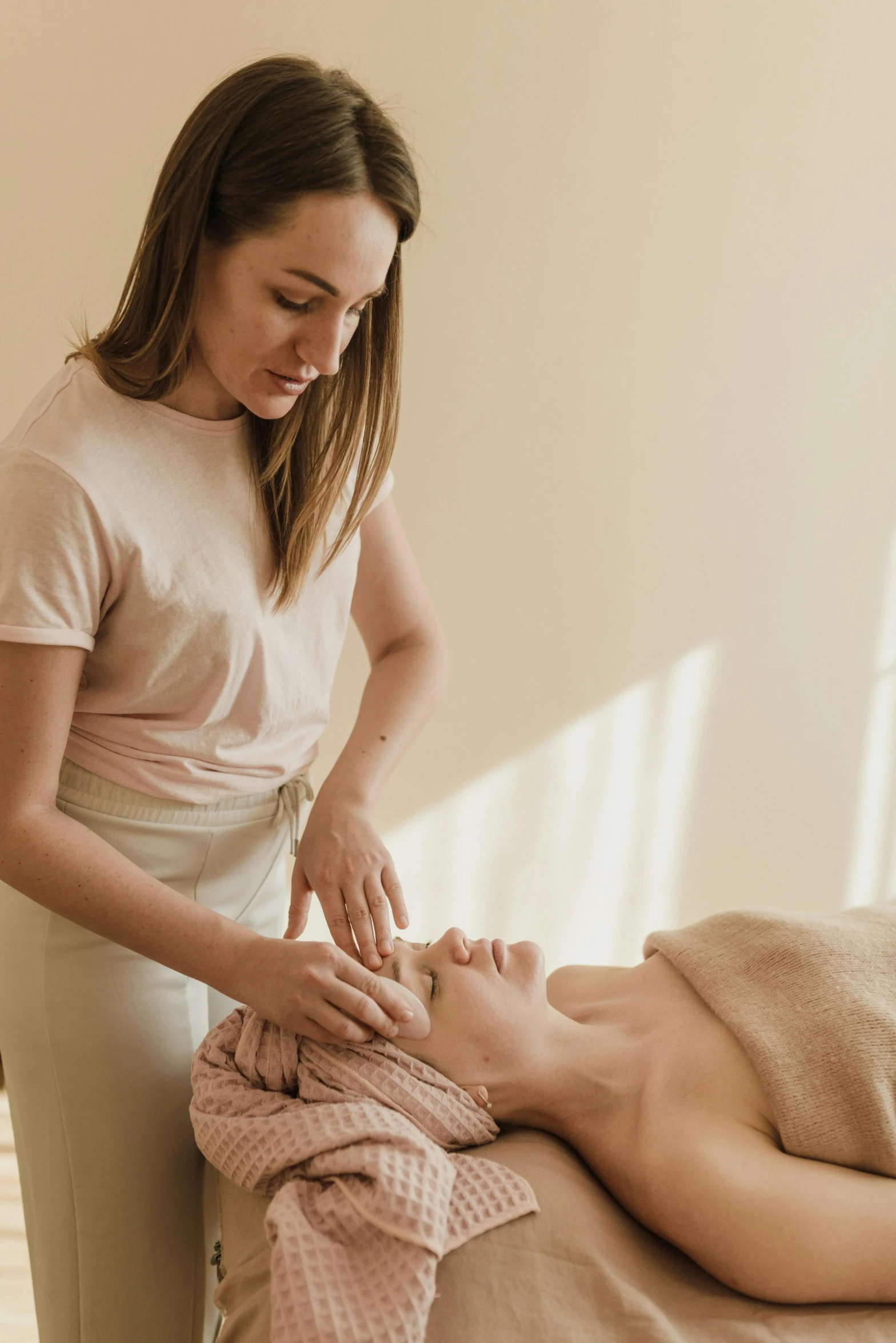 a woman is being offered a facial massage to the woman on a bed