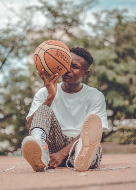 a man is sitting on the ground holding a basketball