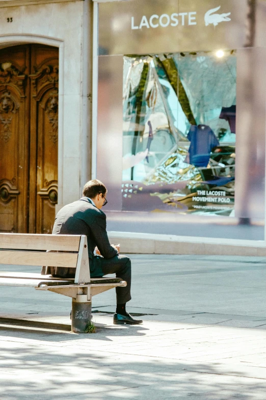 a man is sitting on a bench in front of a store