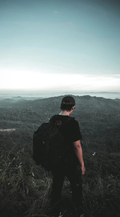 man standing at the top of a tall hill with a backpack on his back