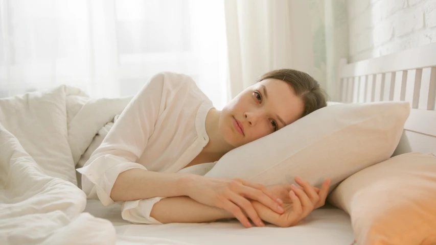 a woman laying in bed and holding a pillow