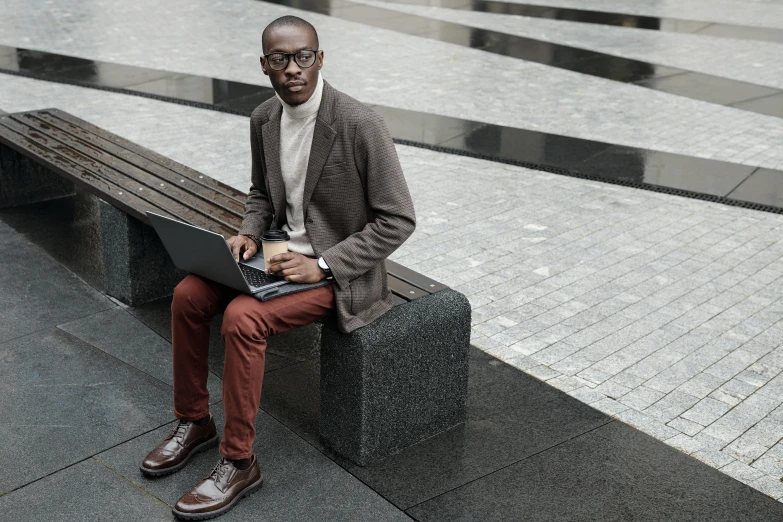 man sitting on a park bench holding his laptop