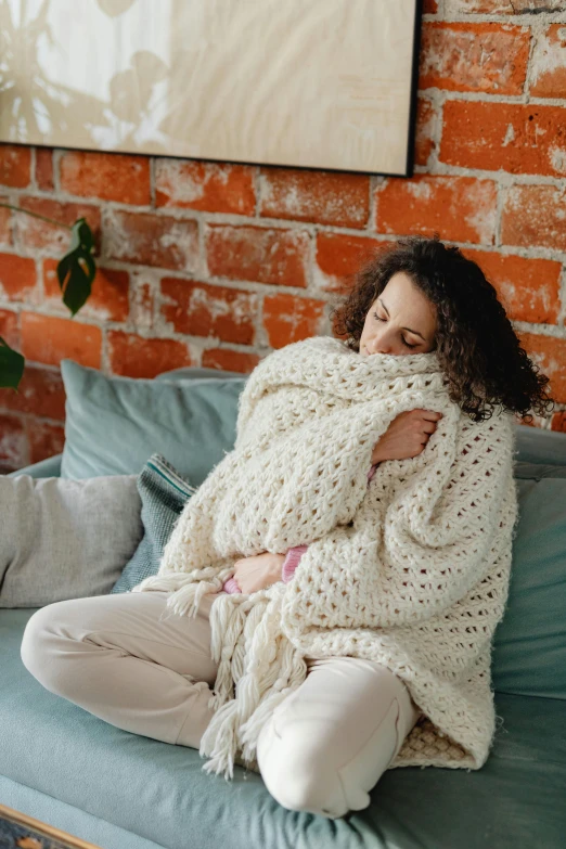 a woman wrapped up sitting on a blue couch