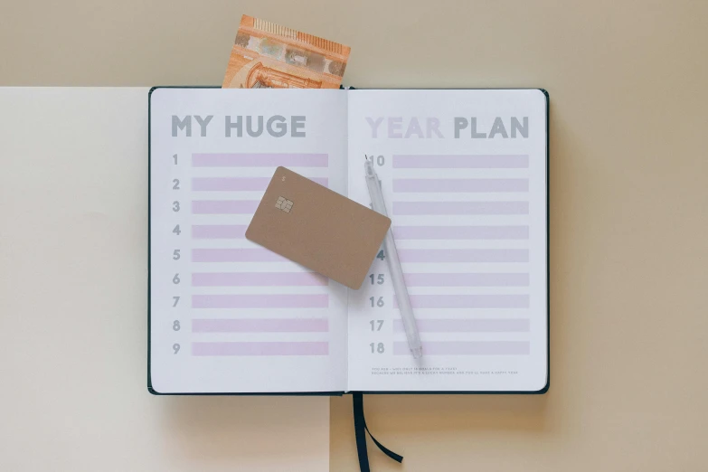 a planner with a pen sticking out of it and some money