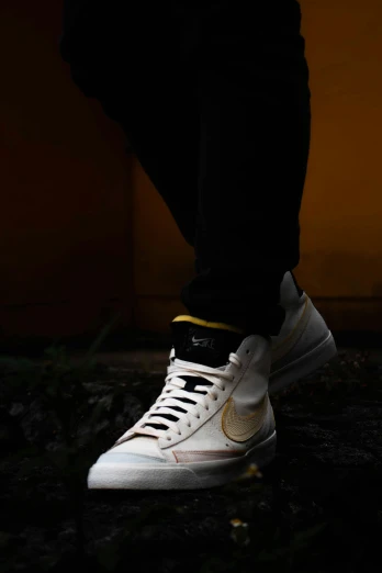 a person with white shoes with a gold logo on them