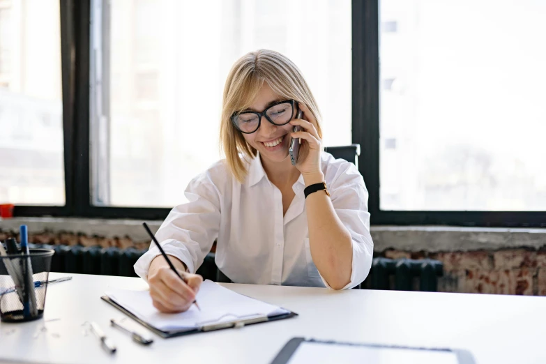 the woman is sitting at a table while using a cell phone