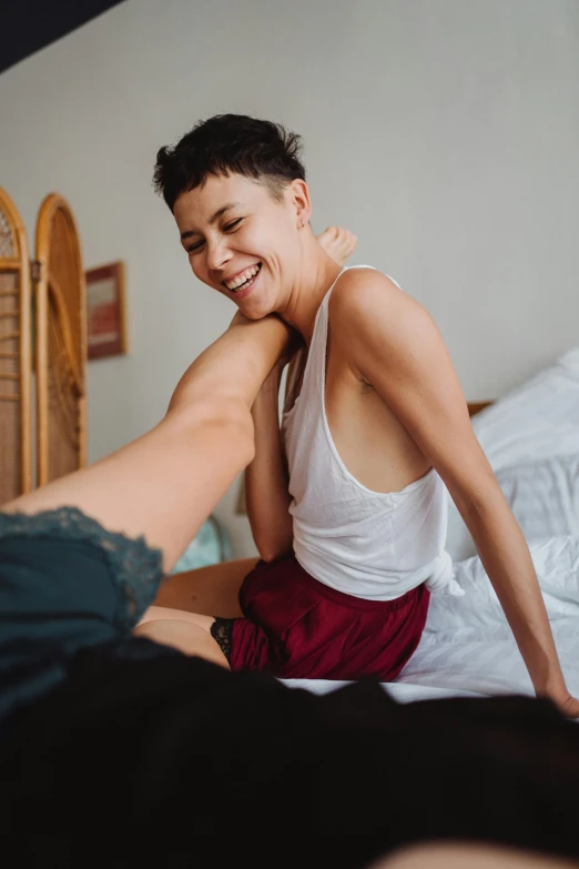 a girl in a white tank top and maroon skirt is getting up from the bed