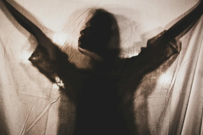 shadow image of person standing next to a curtain