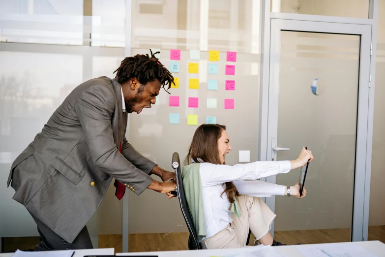 two people in an office setting one with arms outstretched and the other on a chair