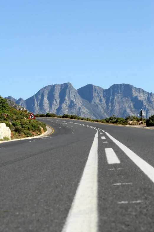 a lone street is at the bottom of the mountains