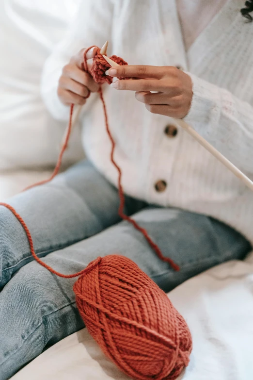 a person holding yarn on a wooden stick