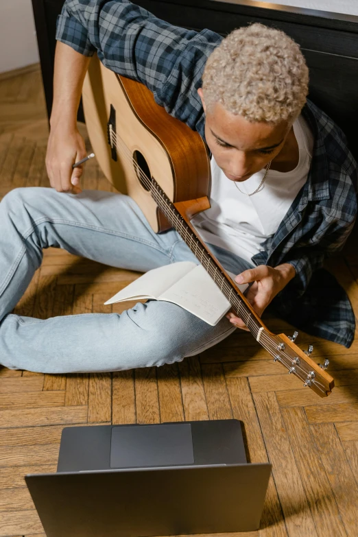 the young man is relaxing playing an acoustic guitar