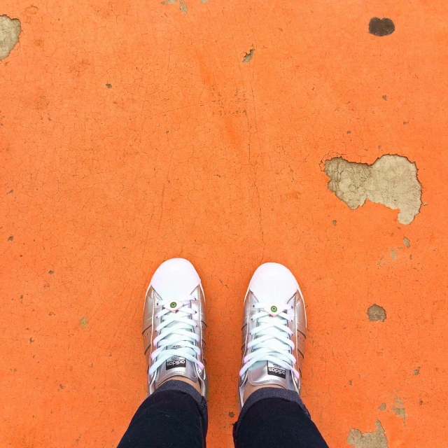 a person is standing on a floor wearing white shoes