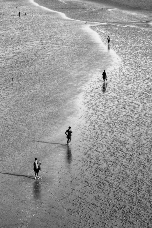 the people are walking down the beach to the water