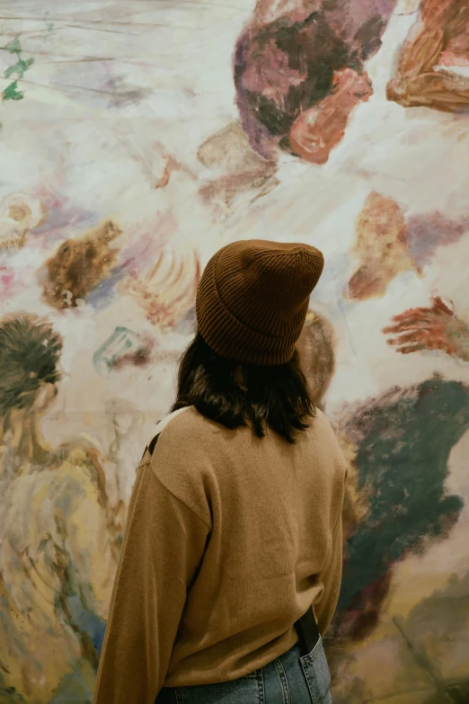 a man with his back to the camera standing in front of a painting