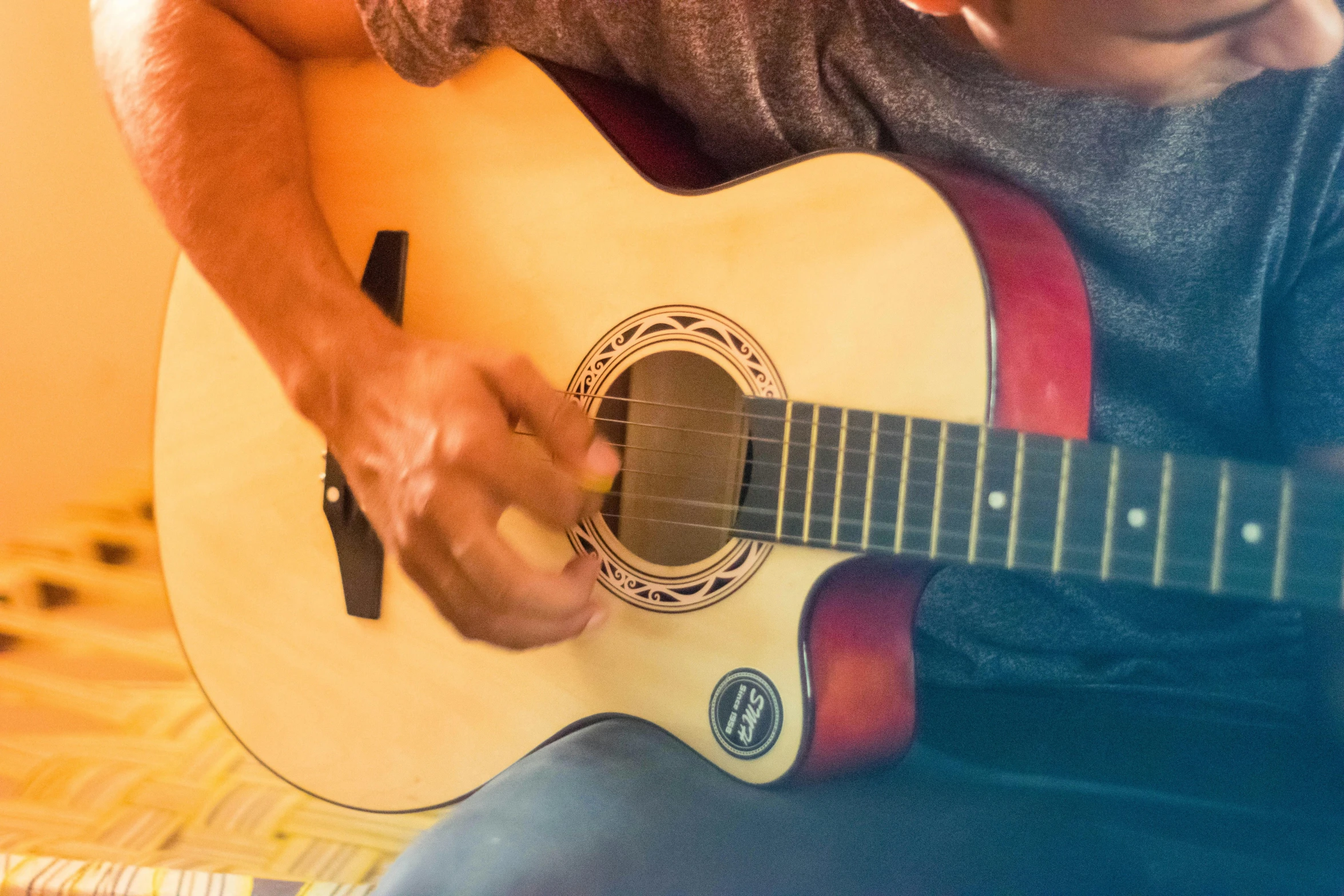 an adult man is playing a guitar while sitting on a couch