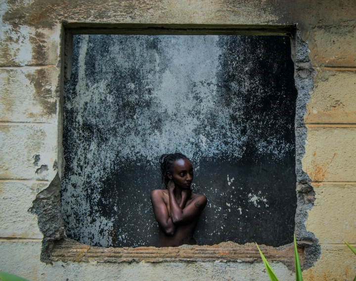 a woman stands behind the barred window of an old building